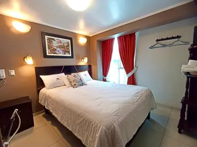 a bedroom with a large white bed with red curtains at Kametza Hotel Ayacucho in Ayacucho