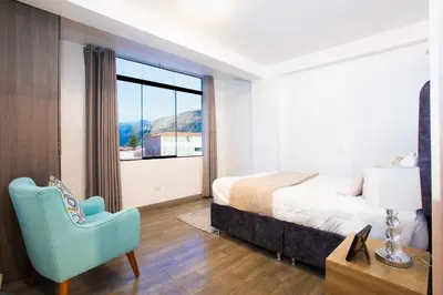 a bedroom with a bed and a chair and a window at Town Center Apartments in Urubamba