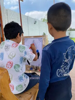 two young boys are painting a picture in a mirror at Hotel La Colina in Ica