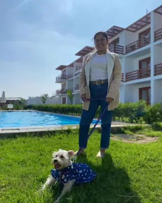 a woman standing next to a dog in the grass at Hotel La Colina in Ica