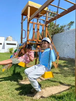 two young children sitting on a swing at Hotel La Colina in Ica