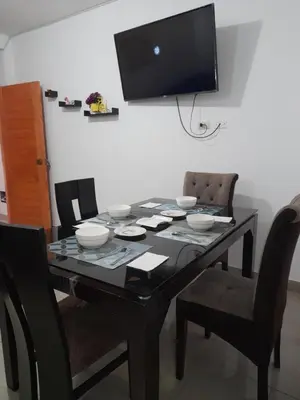 a dining room table with chairs and a television on the wall at Cozy Whole Apartment in Lima