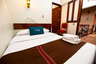 a bedroom with a bed with a blue pillow on it at Hotel Andina in Cusco