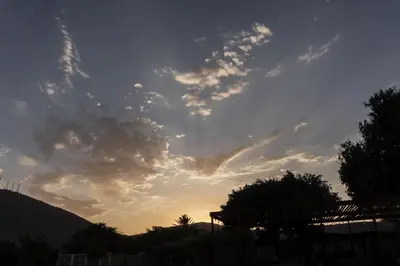 a cloudy sky at sunset with trees and a fence at Casa Solaris in Ica