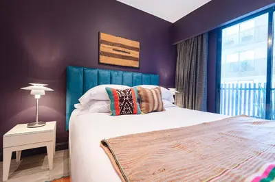 a bedroom with a bed with a blue headboard and a window at ✶ Maras Residence ✶ LUXURY Rooftop Pool & Grill in Lima