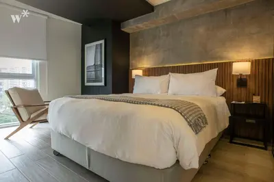 a bedroom with a large bed and a chair at Pionero by Wynwood House in Lima