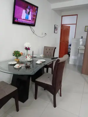 a dining room table with chairs and a television on the wall at Departamento con servicios incluidos, equipado in Lima