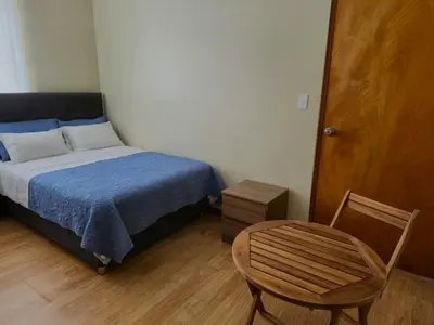 a small bedroom with a bed and a chair at Casa Mahulu in Paracas