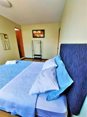 a bedroom with a bed with blue sheets and pillows at Casa Mahulu in Paracas
