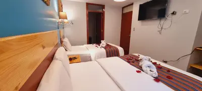 a hotel room with two beds and a flat screen tv at HOTEL LUZ GARDEN in Machu Picchu