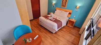 a bedroom with a bed and a table and blue walls at HOTEL LUZ GARDEN in Machu Picchu