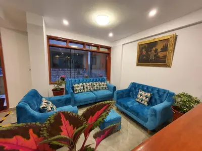a living room with blue couches and a table at HOTEL LUZ GARDEN in Machu Picchu