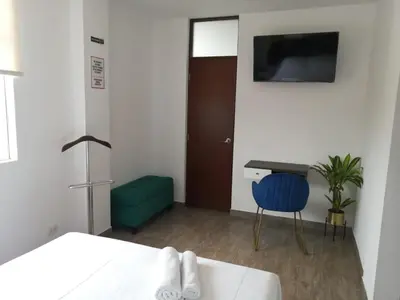 a room with a bed and a desk and a refrigerator at Casa Yuraq Hotel Boutique in Chincha Alta