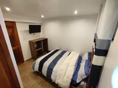 a small bedroom with a bed and a television at linda house cusco in Cusco