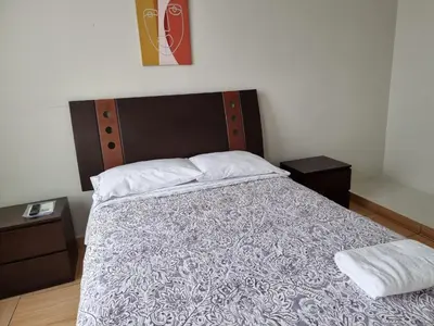 a bedroom with a large bed with a wooden headboard at Apart Hotel Doña Esther in Lima
