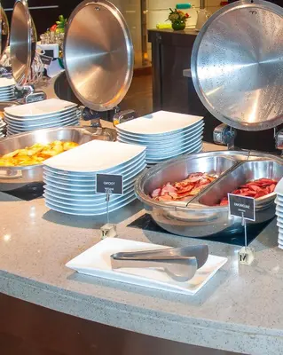 a buffet with plates and pans of food on a counter at Sol de Oro Hotel & Suites in Lima