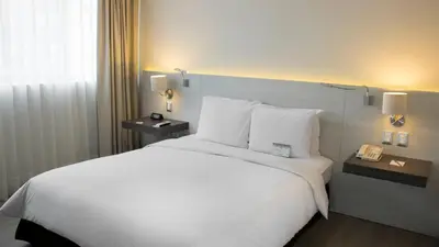 a hotel room with a large bed with white sheets and pillows at Sol de Oro Hotel & Suites in Lima