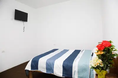 a bed with a blue and white blanket and a vase of flowers at Tiyana House in Cusco