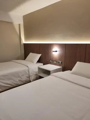 two beds in a hotel room with white sheets at Hotel Rey in Huancayo