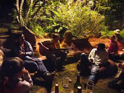 a group of people sitting around a fire pit at Biosfera Lodge tipi para 3 personas in Oxapampa