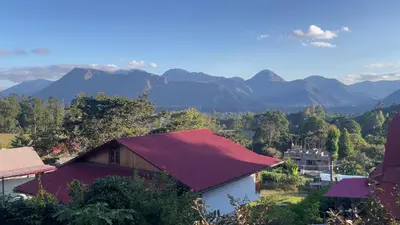 a house with a red roof with mountains in the background at BIOSFERA LODGE GLAMPING tipi 2 personas in Oxapampa