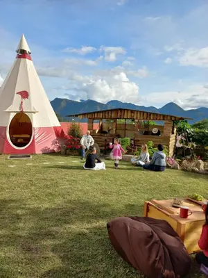 a group of people sitting in the grass near a teepee at BIOSFERA LODGE GLAMPING tipi 2 personas in Oxapampa