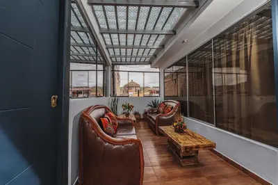a room with two chairs and a table and windows at San Pedro Apartments in Cusco