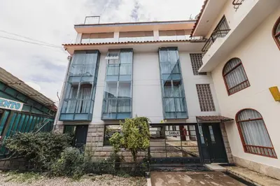 a white building with glass windows and a gate at San Pedro Apartments in Cusco