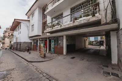 an empty street next to a building with a balcony at San Pedro Apartments in Cusco
