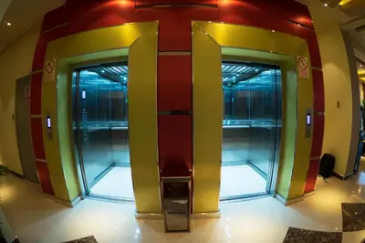 two elevators in a building with glass doors at R&N SHULLKAS SUITES in Huancayo