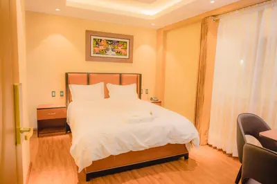 a bedroom with a bed and a chair in it at R&N SHULLKAS SUITES in Huancayo