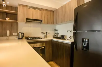a kitchen with a black refrigerator and wooden cabinets at El Sol by Wynwood House in Lima