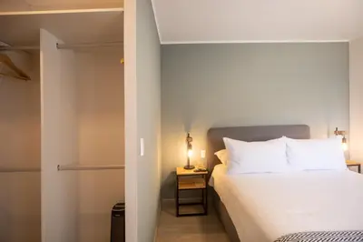 a bedroom with a white bed and a night stand with a lamp at El Sol by Wynwood House in Lima