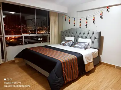 a bedroom with a large bed with a large window at Union Garden Apartments in Cusco