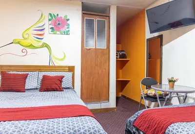 a room with two beds and a tv and a table at Rumi's Inn in Cusco