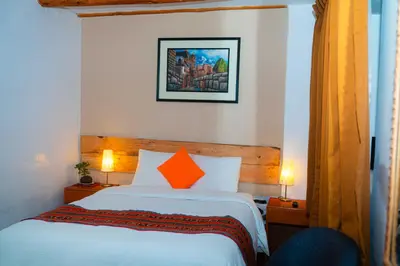 a hotel room with a bed with an orange pillow at Casa de Ollanta ByB in Ollantaytambo