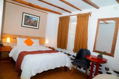 a bedroom with a bed and a chair at Casa de Ollanta ByB in Ollantaytambo
