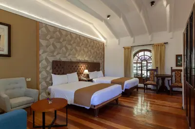 a hotel room with two beds and a chair at Inti Punku Valle Sagrado Hotel in Urubamba