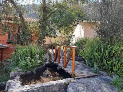 a wooden bridge over a pond in a garden at Inti Punku Valle Sagrado Hotel in Urubamba