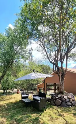 a tree with an umbrella and chairs under it at Inti Punku Valle Sagrado Hotel in Urubamba