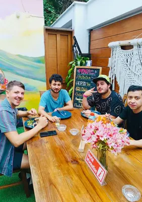 a group of men sitting around a wooden table at Rainbow Hostel in Lima