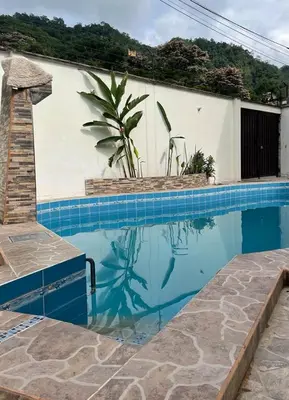 a swimming pool in front of a white wall with a plant at Casa completa piscina 3 Habitaciones en Chanchamayo in La Merced