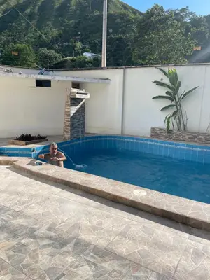 a man in a swimming pool next to a house at Casa completa piscina 3 Habitaciones en Chanchamayo in La Merced
