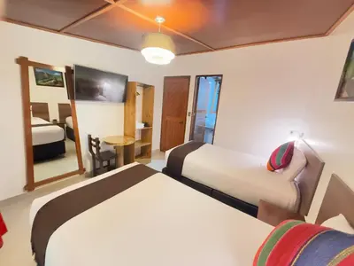 a hotel room with two beds and a television at Inti Pacha Palace Machupicchu in Machu Picchu