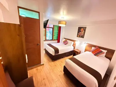 a hotel room with two beds and a door at Inti Pacha Palace Machupicchu in Machu Picchu