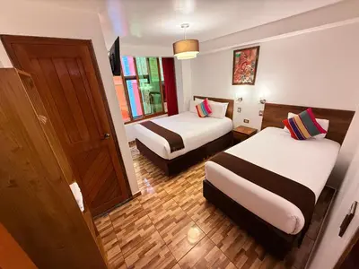 a hotel room with two beds and a door at Inti Pacha Palace Machupicchu in Machu Picchu