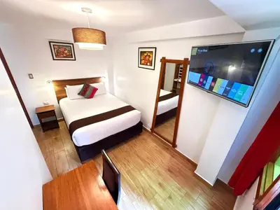 a hotel room with a bed and a flat screen tv at Inti Pacha Palace Machupicchu in Machu Picchu