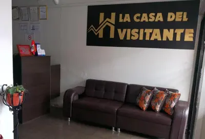 a living room with a couch and a sign on the wall at LA CASA DEL VISITANTE in Cusco