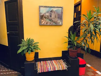 a yellow room with a bench with plants and a picture at KORICANCHA in Lima