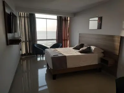a bedroom with a bed and a view of the ocean at Hotel Terrazas Del Mar in Huacho